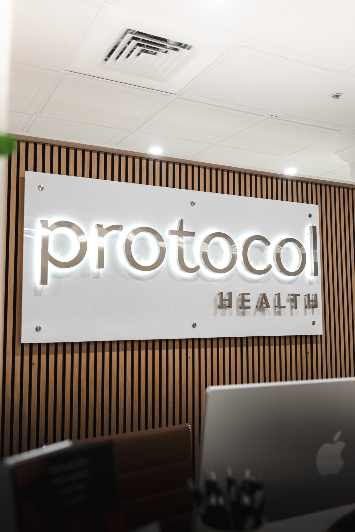 The Protocol Health sign on the wood-slat wall at the Scarsdale clinic's front desk