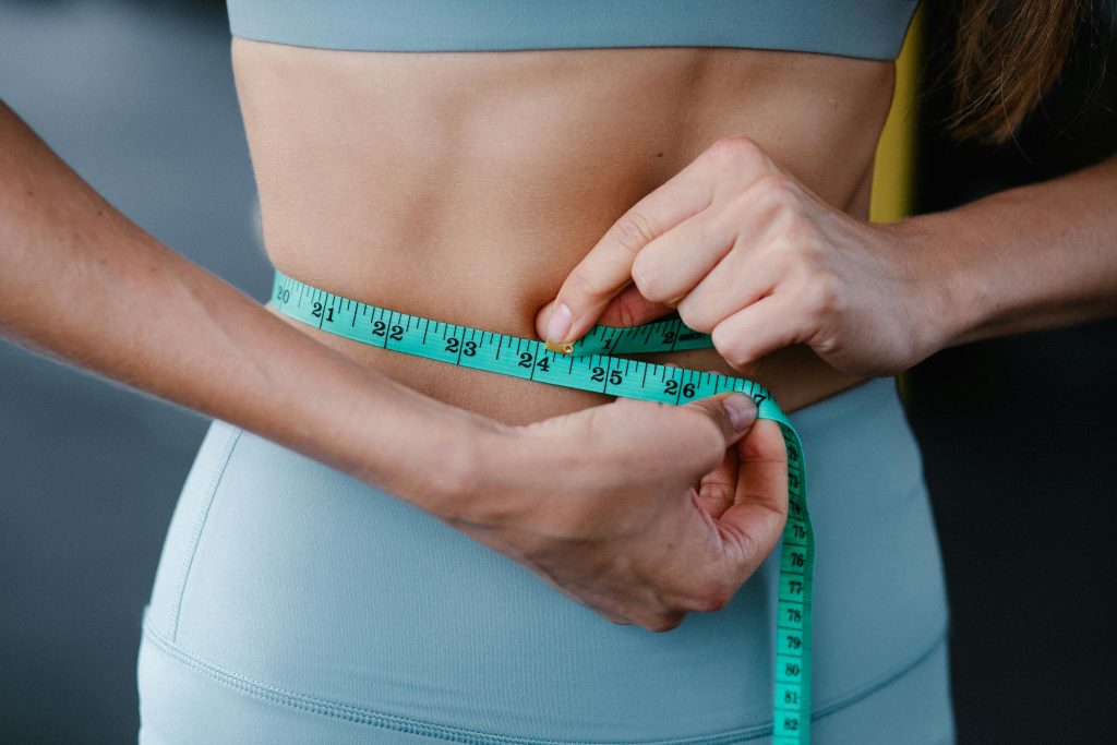 Person measuring their waistline for weight loss