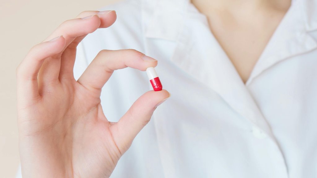 A woman holding a pill