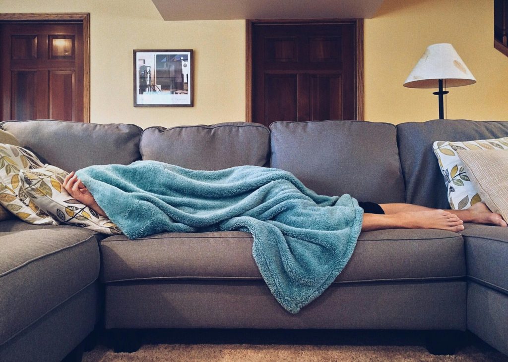 Person sleeping on a couch under a blanket